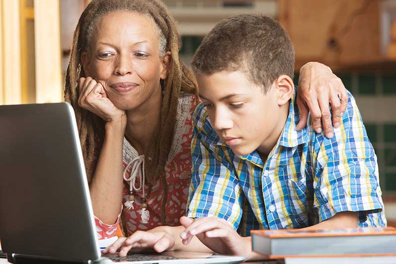 Teenage boy on laptop with parent