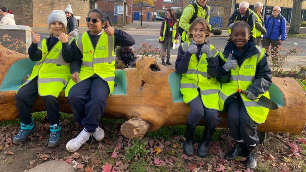 School children sit on the carved logs at Southgate Pocket Park