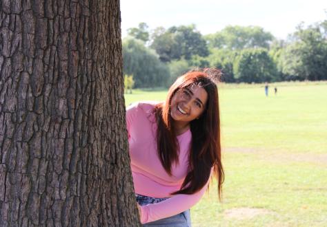 Girl standing behind tree