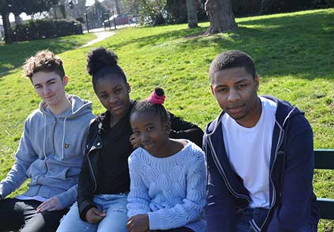 4 children sitting on a park bench