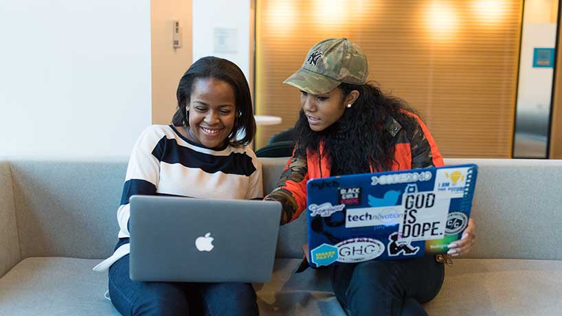 Two women working with laptops on their laps
