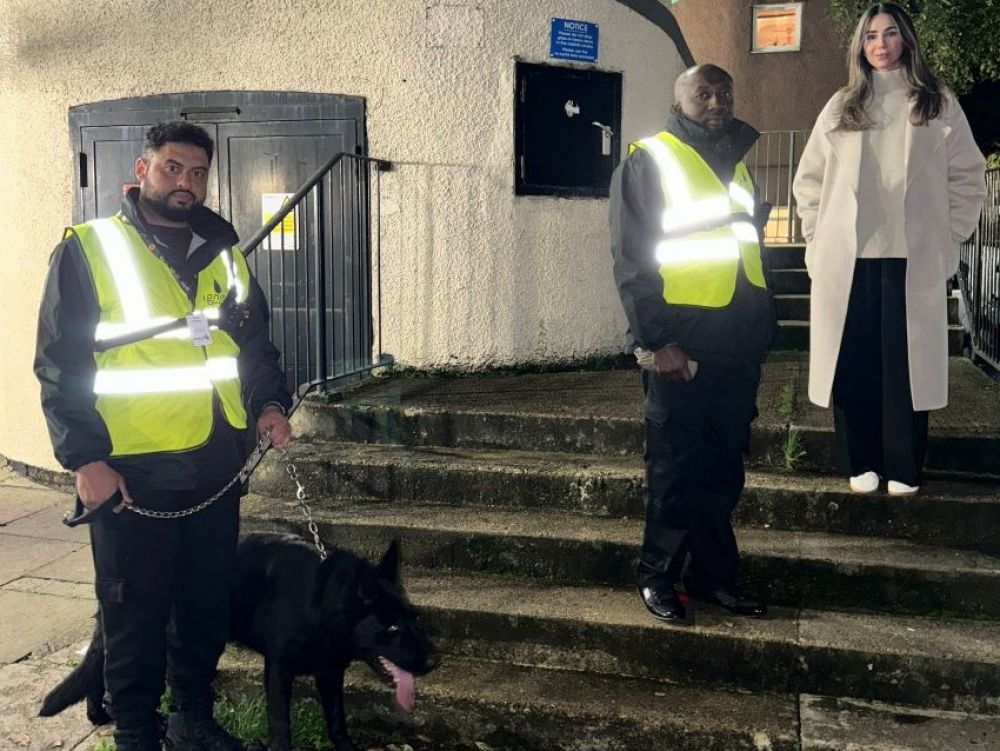 Cllr Guzel on the steps of the Avenues Estate with two security guards and dog