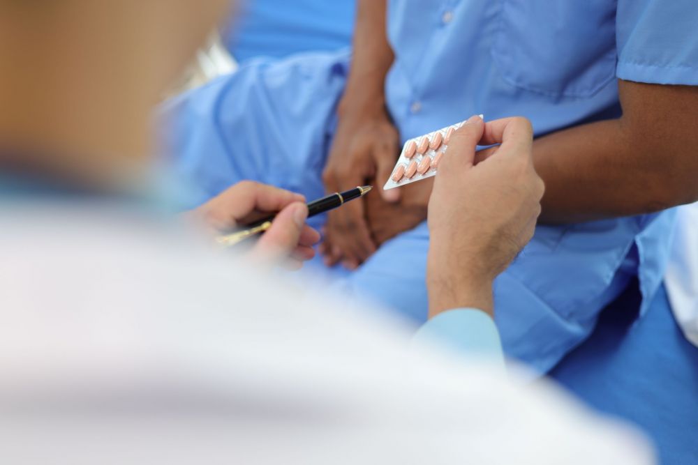 A man receives some pills from a clinician